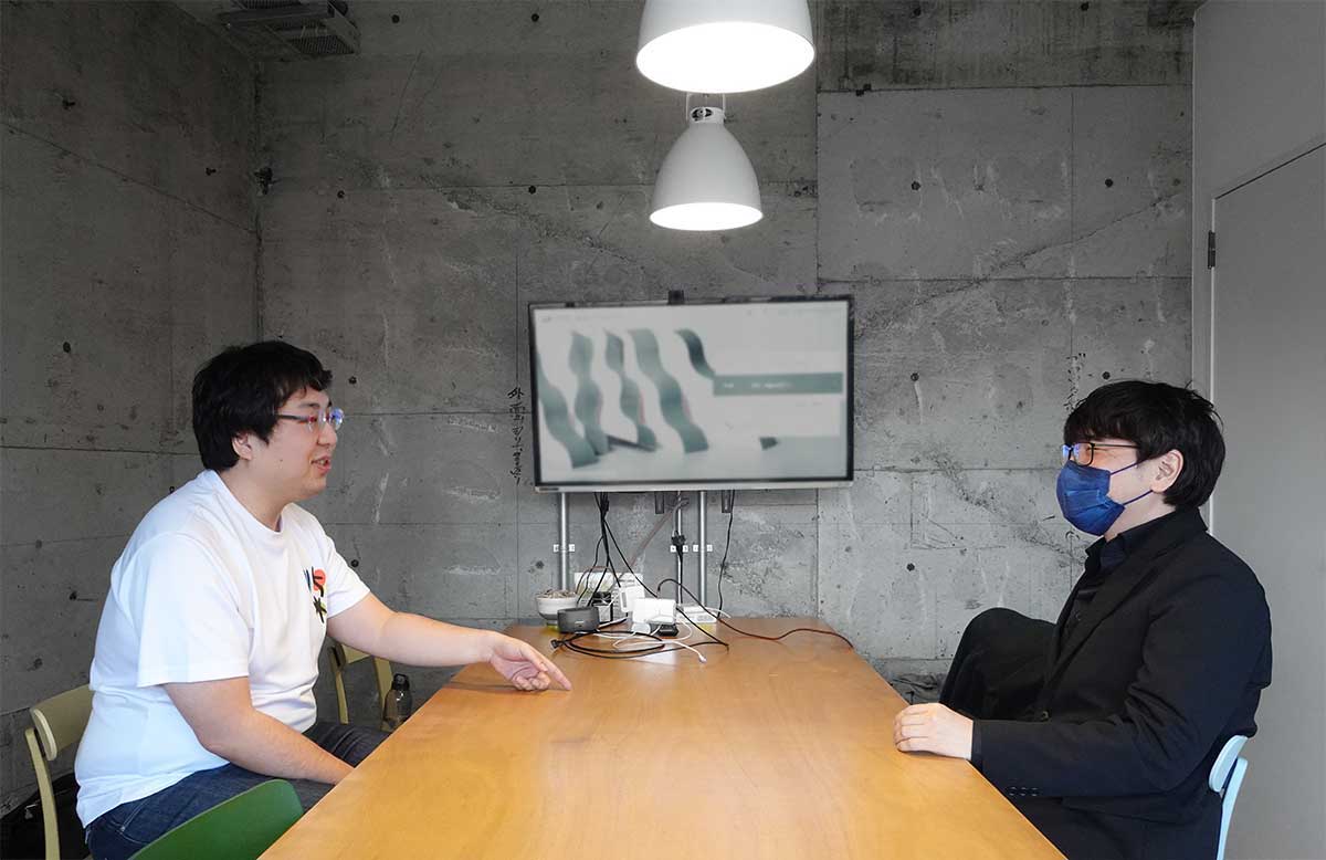 カヤックのオフィスで話す柴田さんとフジイ。机を挟んで楽しそうに話している