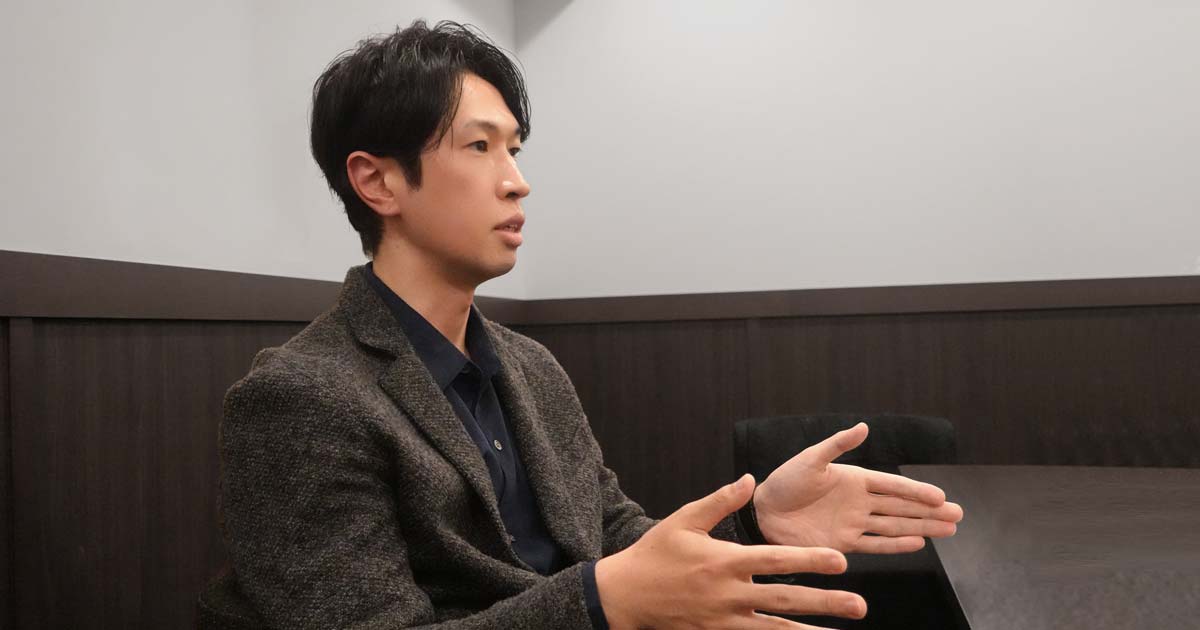 インタビュー中の神谷さん。横からのアングルで両手のひらを前に出して話している