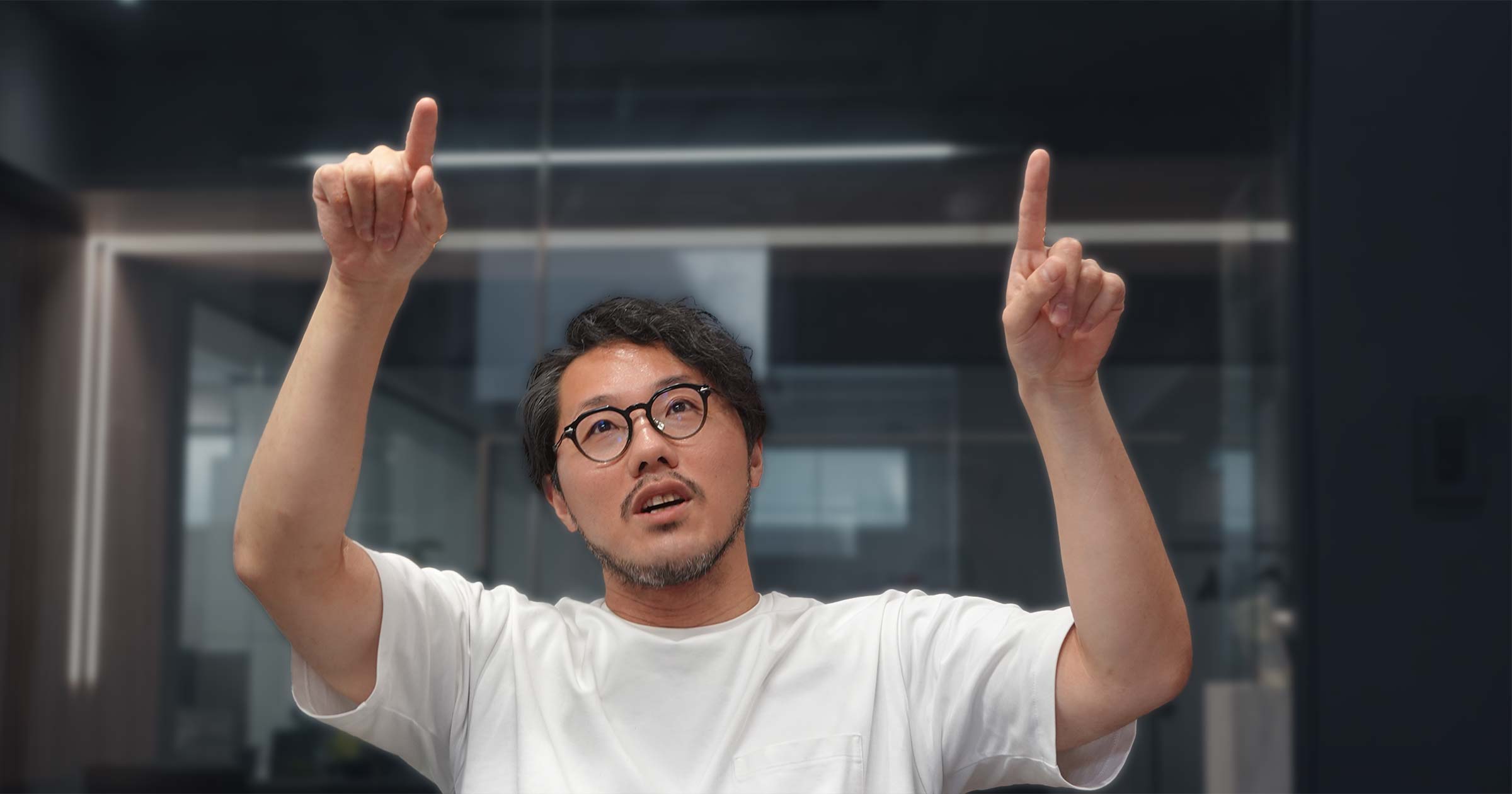 両手で上を指しながら話すミナベさん